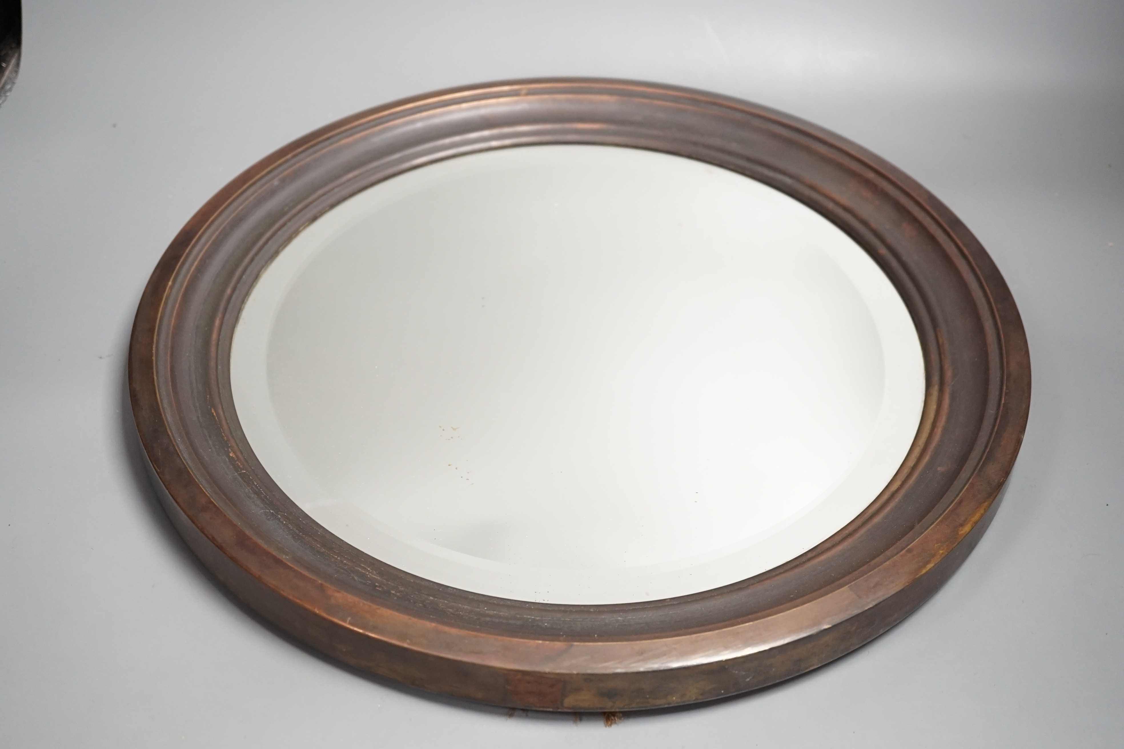 A brass framed circular mirror ‘ALBANY MIRROR BRITISH MADE PAT No 10405 203041-236189’ to reverse and a copper framed mirror, largest 43 cms diameter.